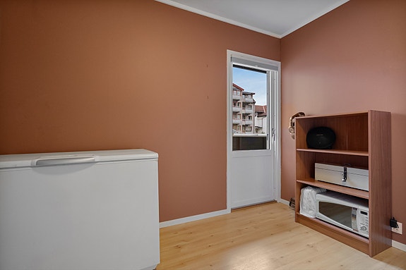 Rommet har en varm fargetone som gir en lun atmosfære, og direkte utgang til leilighetens private balkong