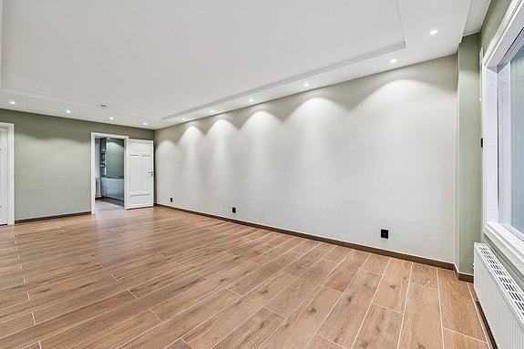 En stue som innbyr til både hverdagshygge og selskap - med mange spotlights i taket som skaper en lun og moderne atmosfære.