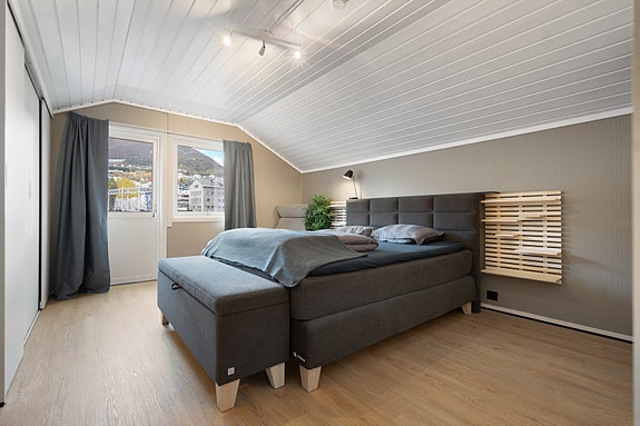 Soverommet har store vinduer og utgang til liten balkong med utsikt over nærområdet - perfekt for å nyte morgenkaffen i frisk luft