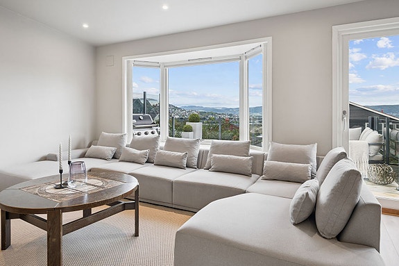 Stue med nydelig utsikt over Drammen by og trivelig plass til sofagruppe.