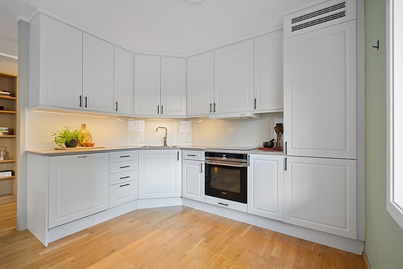 Stilrent og moderne kjøkken med god benkeplass og tidløse fronter i hvitt. Praktisk utforming som gjør matlagingen både enkel og effektiv