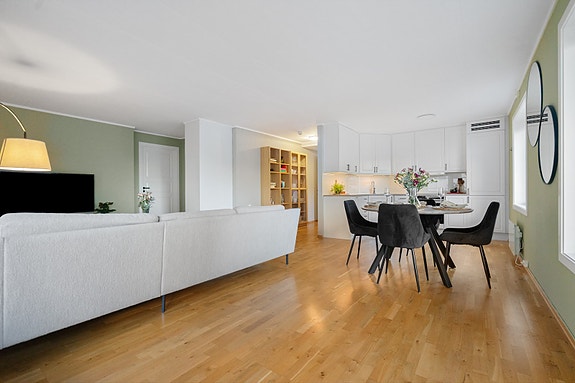 Stuen har både plass til sofagruppe og spisebord. En hyggelig sone for samvær og avslapning - midt i hjertet av leiligheten