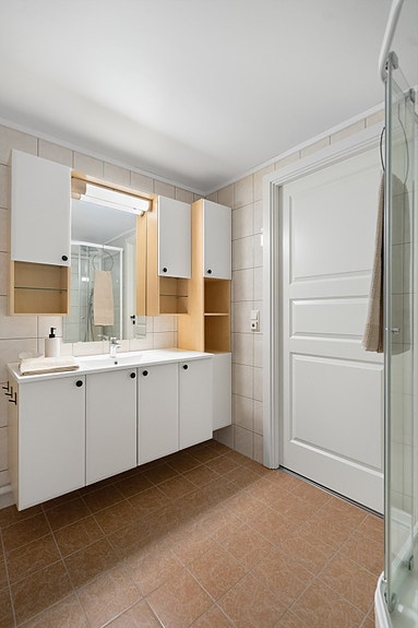 Lys innredning med speil og god belysning gir rommet et ryddig og innbydende uttrykk