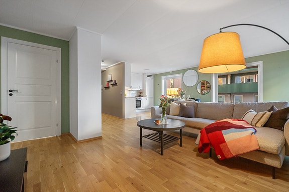 Åpen løsning mellom stue og kjøkken skaper en sosial sone med naturlig flyt mellom matlaging og samvær