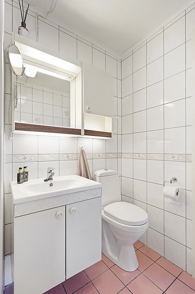 Badet har innredning med nedfelt servant, toalett og dusjvegger/hjørne