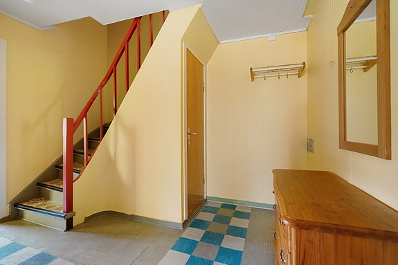 Romslig hall med oppbevaringsmuligheter og trapp som leder opp til boligens andre etasje