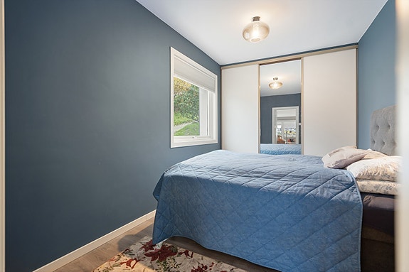 Soverom 1 - Rolig atmosfære med lune blåtoner og naturlig lys fra vinduet gir et avslappende uttrykk