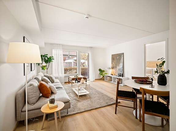 Lys og lekker stue med store vindusflater, splitter nye vinduer og balkongdør. Alt er pusset opp — gulv, tak og vegger i lyse, trendy farger gir et moderne og friskt uttrykk. Her er det bare å flytte rett inn!