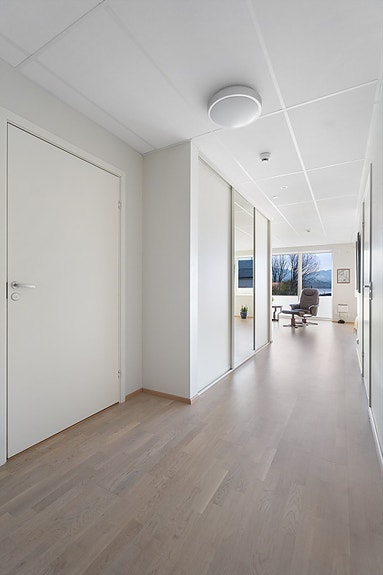 Lys og innbydende gang som binder rommene sammen og leder videre mot bad, stue og kjøkken