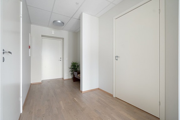 Romslig gang med lyse overflater. Leiligheten har en praktisk planløsning