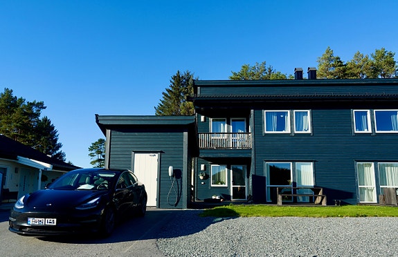 Pen fasade i tre med utebod. På eiendommen er det plass til tre bilar, i tillegg til plen og terrasse.