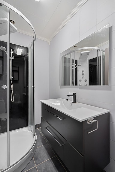 1.etg. - Badet er innredet med romslig servant med skuffer, dusjkabinett og toalett