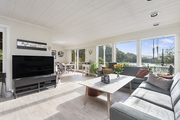 Stuen har store vindusflater som gir godt med naturlig lys og utsyn til grønne omgivelser. Foto: Fotograf Morten Fasseland AS