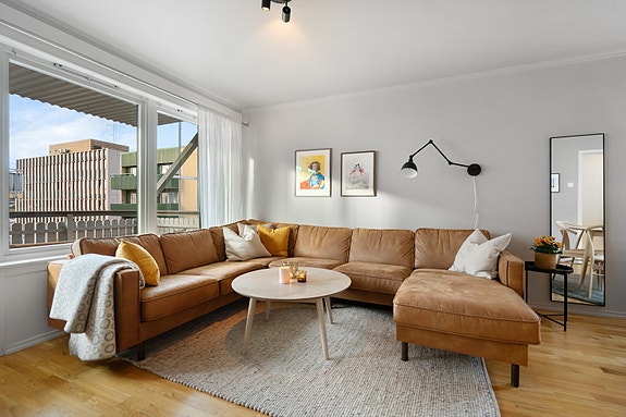 Sofasonen har en fin plassering mot store vinduer og utgang til balkongen - et herlig sted å nyte roen i hverdagen