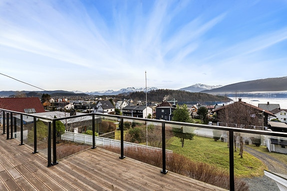Stor terrasse fra stuen med glassrekkverk og praktfull utsikt
