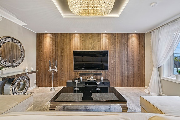 Stilren stue med moderne overflater og behagelig lyssetting.