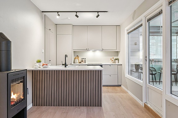 Moderne kjøkken fra 2025 med kjøkkenøy og slette fronter, elegant integrert i stue- og kjøkkenløsning.