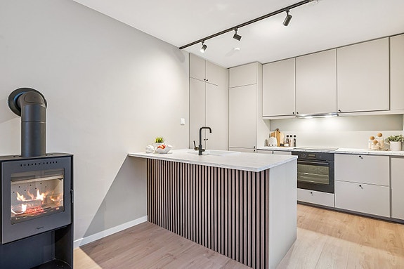 Gjennomført og moderne kjøkken som balanserer sosialt samvær og praktisk bruk på en elegant måte.