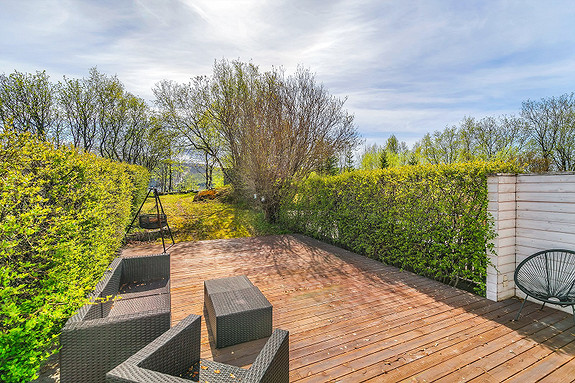 Skjermet og frodig uteområde med terrasse og hage.