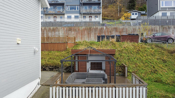 Boligen har også flotte utearealer. Her ser dere en terrasse ved siden av boligen, samt en gapahuk som står på borettslagets felles tomt.