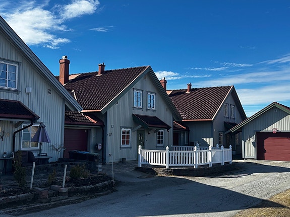 Forsiden av huset med gjerde som rammer inn eiendommen. God plass til utemøbler.