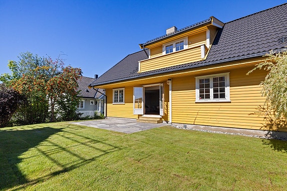 En flott uteplass med god boltreplass for barna i skjermet og solfylt hage.
