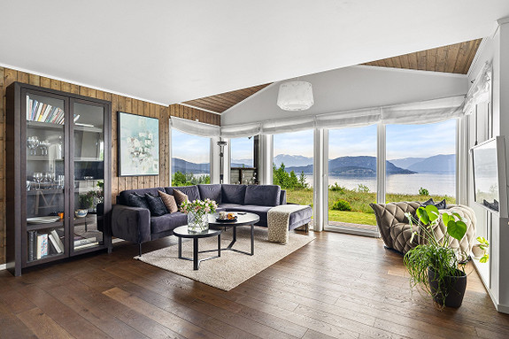 Stue med store vindusflater med utsikt over fjord og fjell