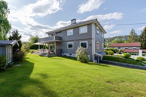 Hus og hage ligger skjermet og tilbaketrukket fra den rolige veien. Rett ved populære Gressbanen. Hagen man ser i front her pluss ut i hjørnet til venstre disponeres eksklusivt av boligen for salg.
