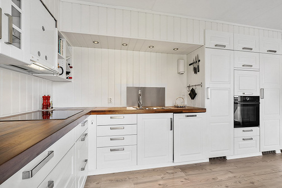 Stilig, stort kjøkken med rikelig benkeplass og med downlights.