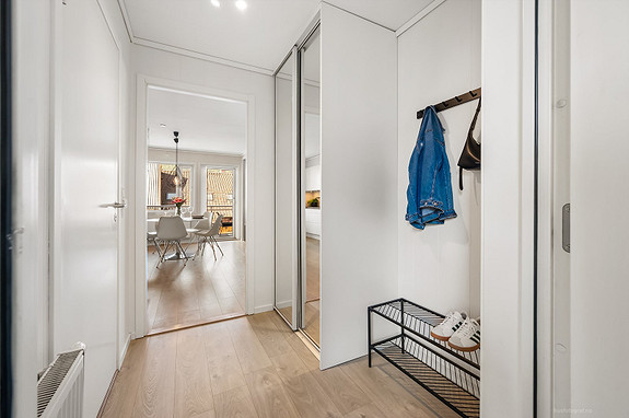 Lys og innbydende entré med skyvegarderobe og delikate, lyse overflater.