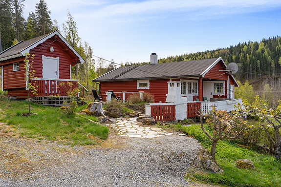 Velkommen til Bottenvika 21
Rød hytte med terrasse og et mindre uthus. Gruslagt innkjørsel, steinbelagt gangsti og omgitt av skog.
