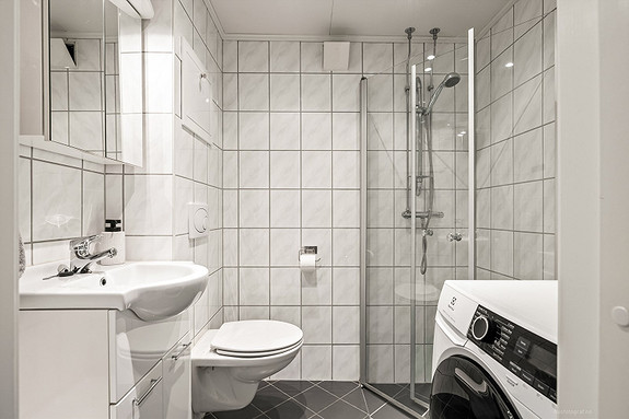 Moderne baderomsinnredning med opplegg for vaskemaskin.