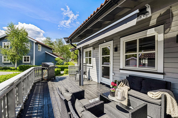 Romslig terrasse med god plass for utemøbler, grill og med utgang til hage.