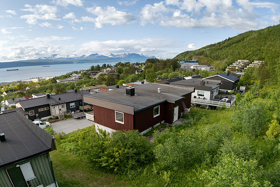 Tomten er skrånet og opparbeidet med plen og noe beplantninger