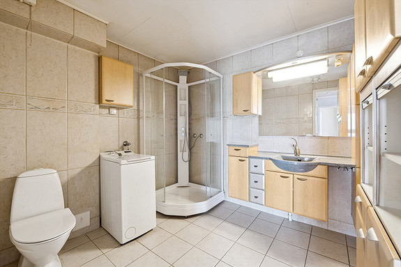 Badet er flislagt med opplegg til vaskemaskin.