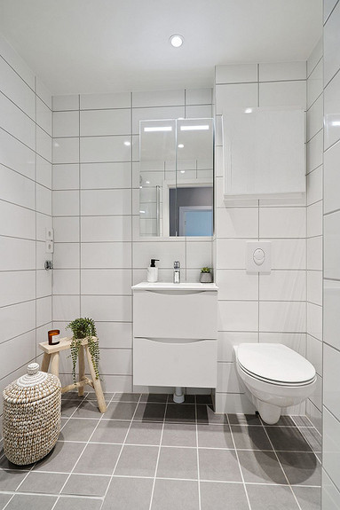 Stilrent bad med downlights i tak, fliser på gulv og vegger, og smarte oppbevaringsløsninger.