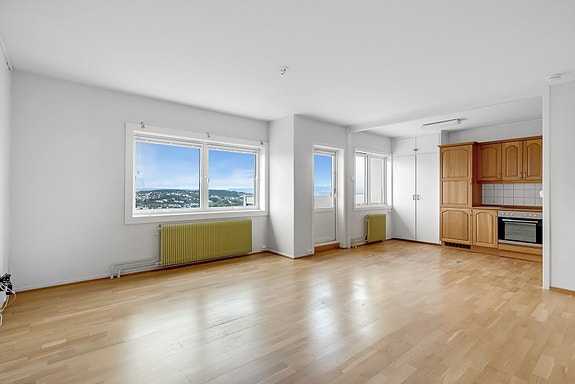 Åpen stue- og kjøkkenløsning med eikeparkett og store vindusflater for en luftig atmosfære.