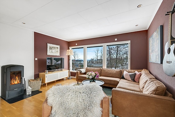 Stue i hovedetasje med vedovn og utsikt.