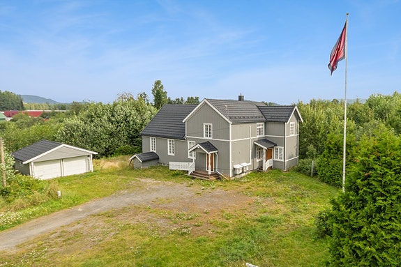 Stor og innholdsrik enebolig med frittstående dobbelgarasje på en romslig tomt.