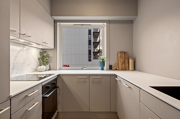 Flis over deler av benk. Integrert komfyr, oppvaskmaskin, kjøl og frys, type Electrolux. Induksjonstopp, type Electrolux