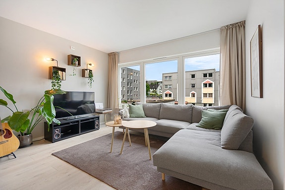 Stue med lyse farger og store vindu som slipper inn rikelig med naturlig lys