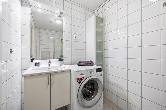 Moderne baderomsinnredning med opplegg for vaskemaskin.
