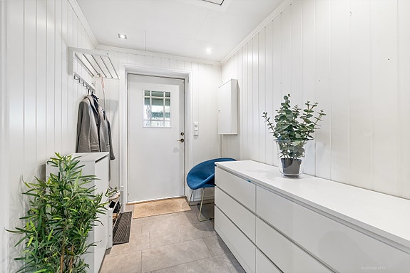 Lys og innbydende entré med moderne oppbevaringsløsninger og plass til sittemøbel.