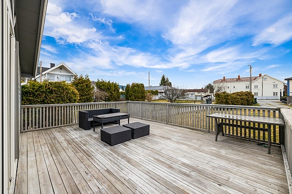 Romslig terrasse med god plass for utemøbler, ideell for sosiale sammenkomster, omgitt av et fredelig nabolag.