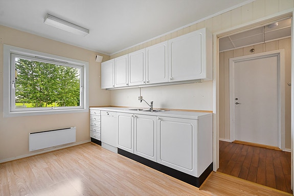 Lyst kjøkken med hvite fronter og god plass til spisebord ved vinduet