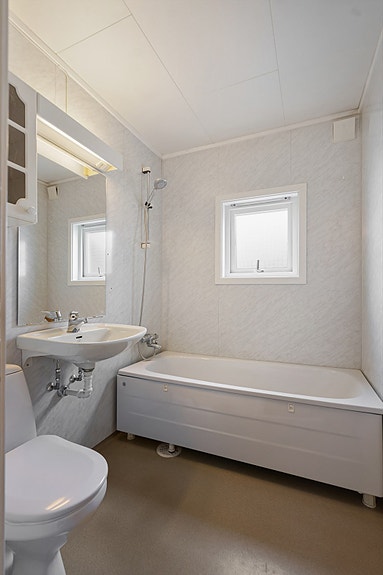 Lyst bad med kombinert dusj og badekar, servant og toalett