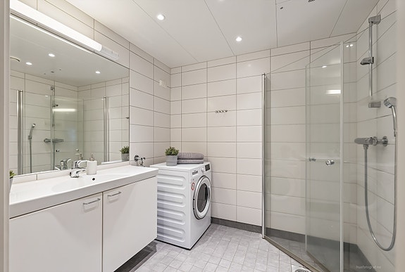 Moderne baderomsinnredning med opplegg for vaskemaskin.