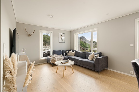 Stuen har moderne farger og plass til både sofagruppe og spisebord.