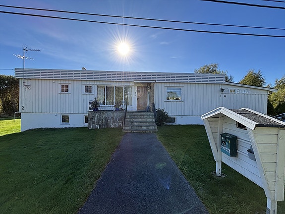 Boligen har stående bordkledning og en trapp med smijernsrekkverk som leder til inngangspartiet. Velkommen inn.