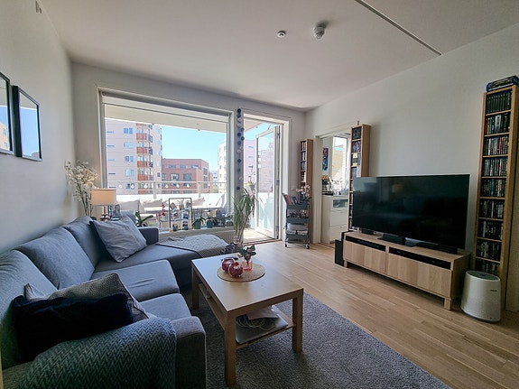 Åpen kjøkkenstue med mye naturlig lys og utgang til balkong.